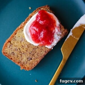 The Ultimate Moist Banana Bread 6 A slice of moist banana bread served on a small plate with a thick spread of jam.