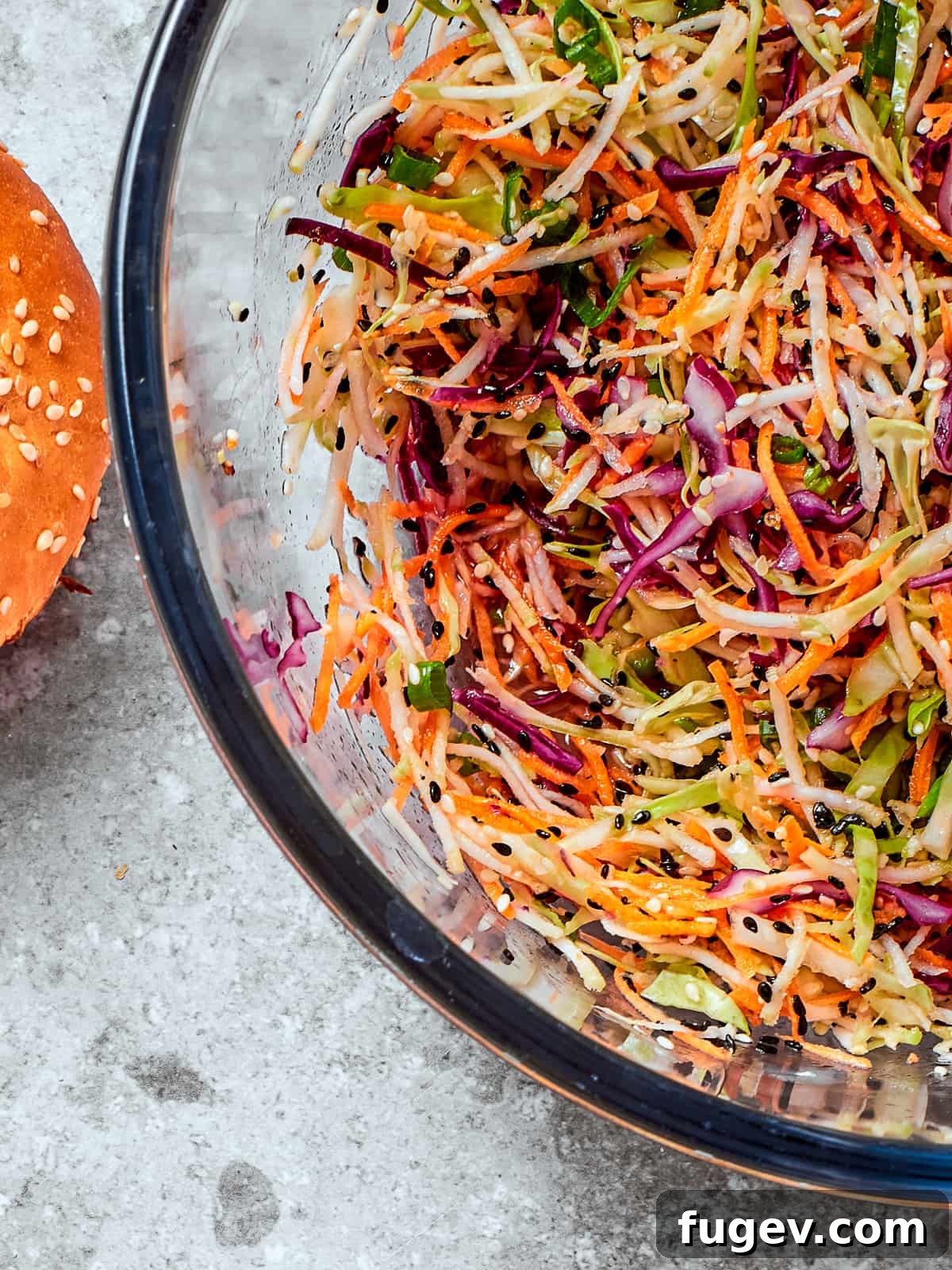 Wholesome Crunchy Broccoli Slaw 2 Healthy broccoli slaw served in a clear glass bowl showing off colors and textures of the dish.