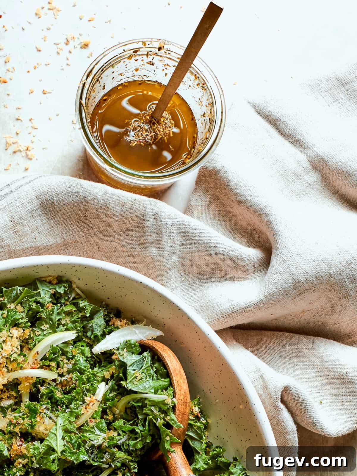 Effortless Homemade Italian Dressing 7 A stylish clear jar of Italian salad dressing resting on a wooden surface next to a soft, folded cloth napkin, highlighting its rustic appeal.