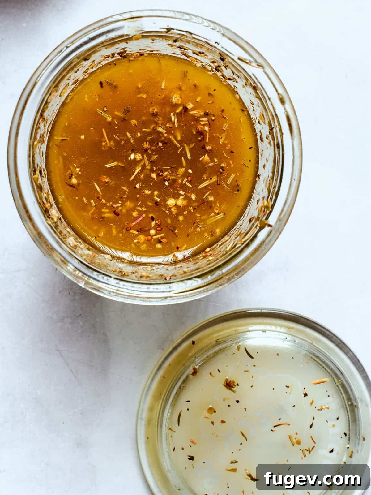 Effortless Homemade Italian Dressing 8 A clear glass jar brimming with homemade Italian salad dressing, prominently displaying the vibrant herbs and spices suspended within the golden liquid.