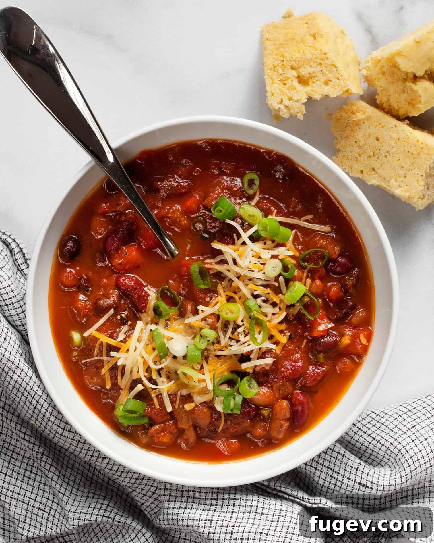 Hearty Bean Chili Delight 2 Three bean chili in a bowl with a side of cornbread, garnished with fresh cilantro and a dollop of sour cream.
