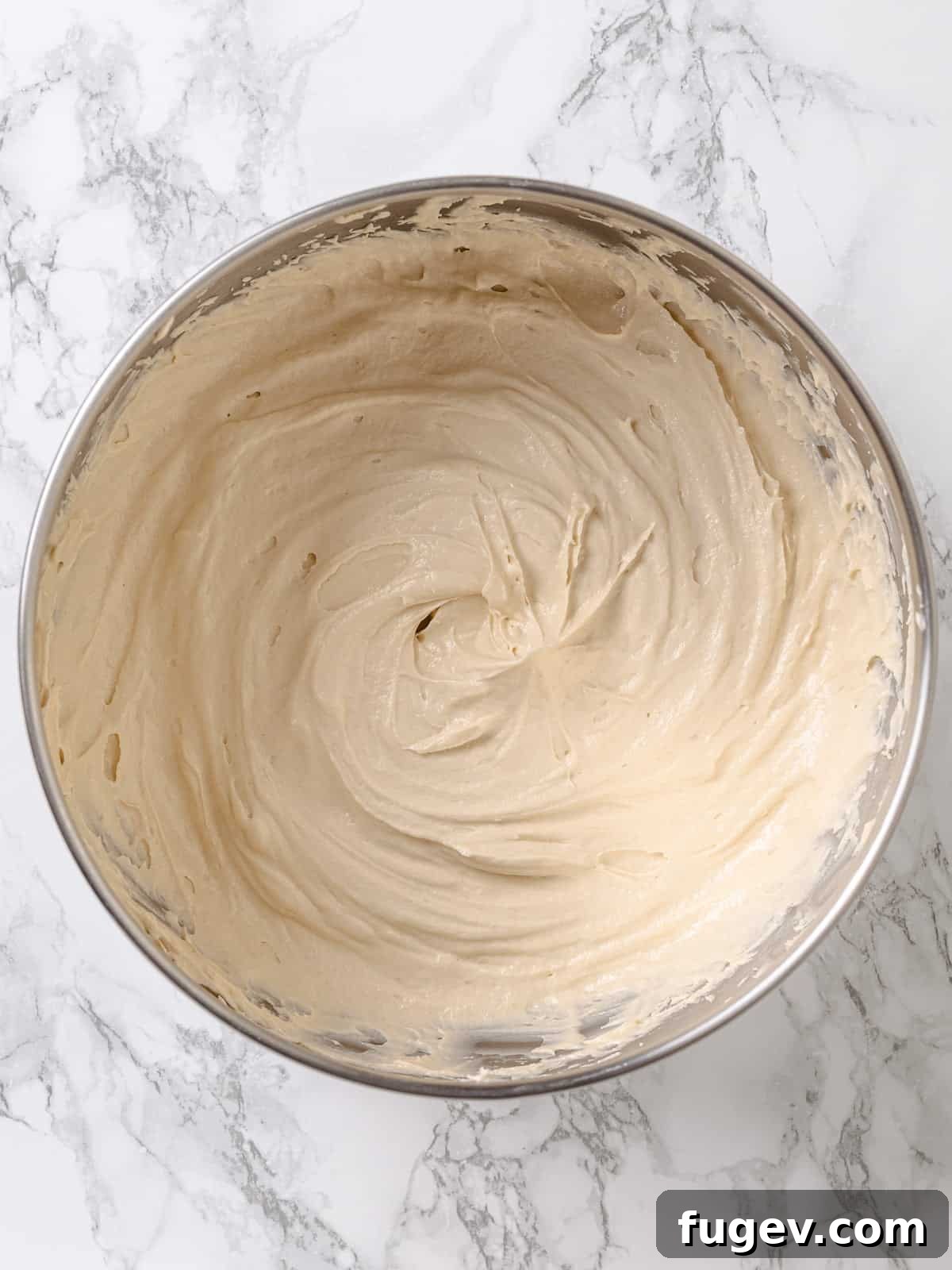 Golden Maple Delight 12 A large bowl filled with freshly prepared, fluffy maple frosting, ready for use.