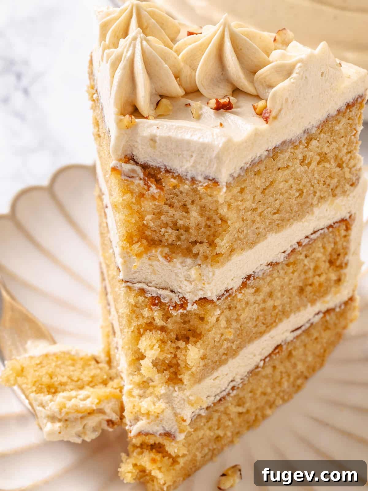Golden Maple Temptation 2 Fork holding a bite of three-layered maple cake with frosting between each layer, showing its moist crumb.