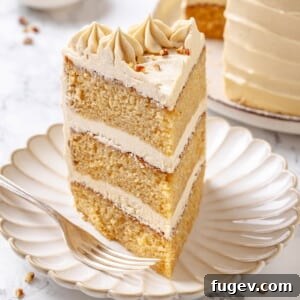 Slice of maple cake on a white plate with visible layers of cake and frosting.