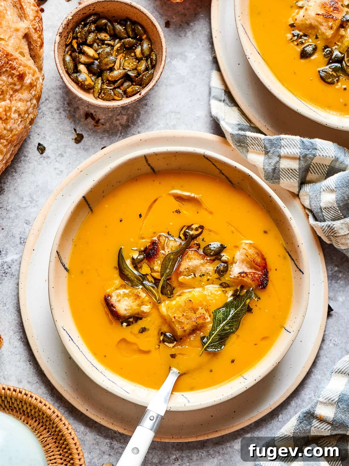 Golden Harvest Squash Soup 15 creamy squash soup in a bowl, garnished with black pepper and herbs.