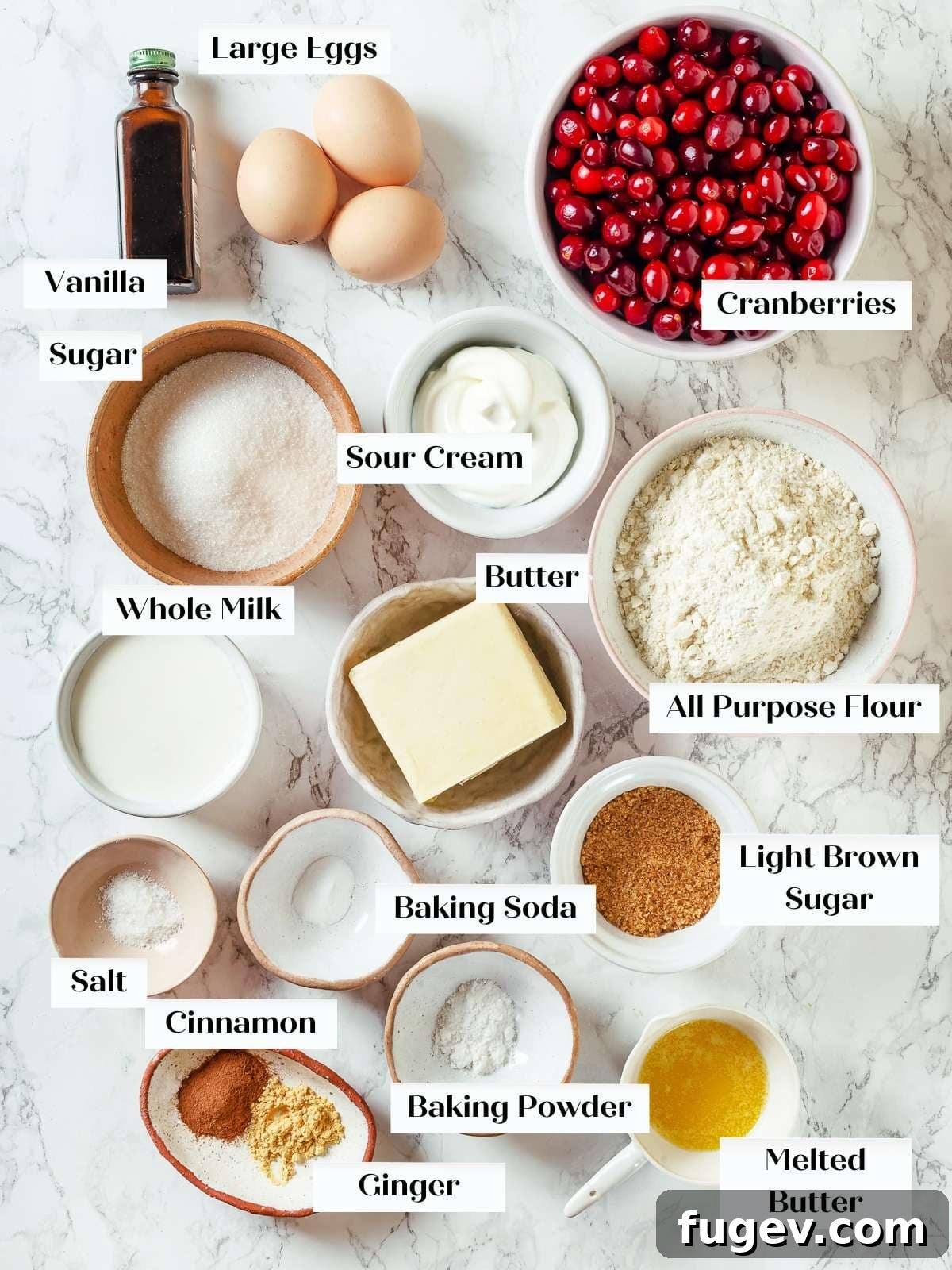 Ultimate Cranberry Cake 3 Measured ingredients for cranberry cake laid out neatly on a white kitchen counter, including flour, sugar, butter, eggs, cranberries, and spices.
