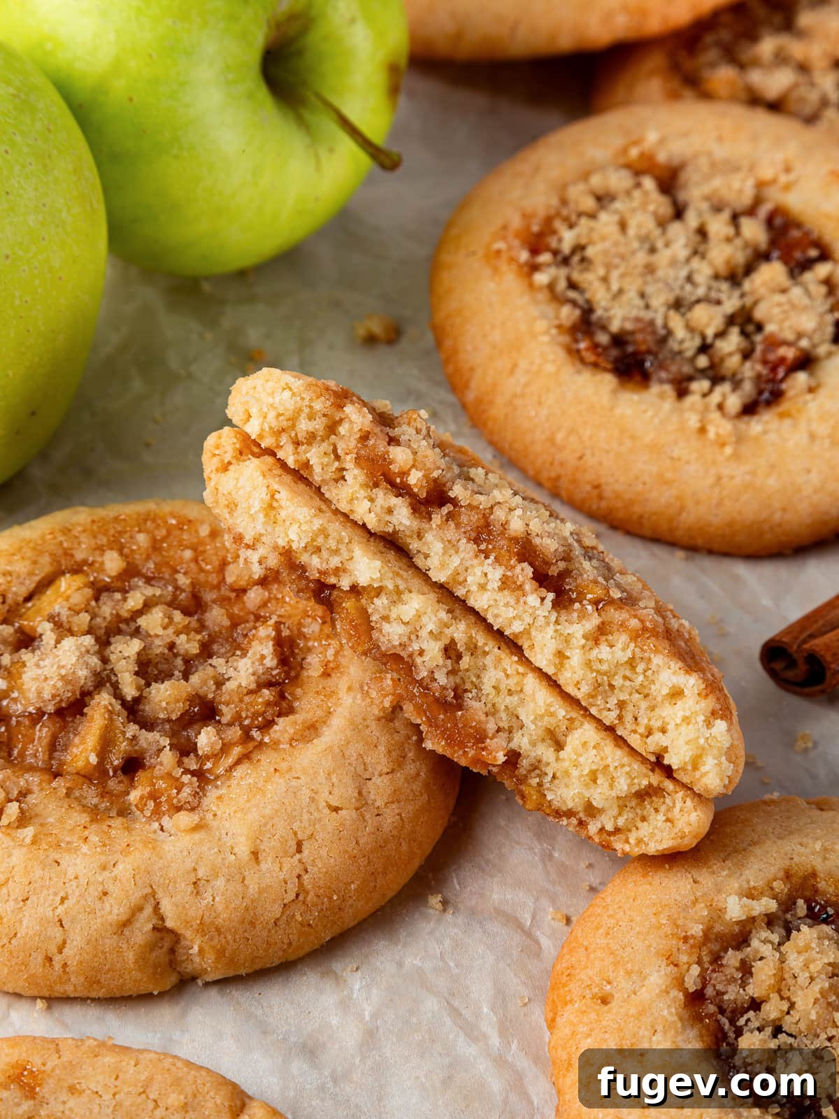 Warm Apple Spice Cookies 2 A perfectly baked apple pie cookie broken in half, revealing its irresistible gooey apple filling inside a chewy brown sugar dough, showcasing the delicious texture and filling.