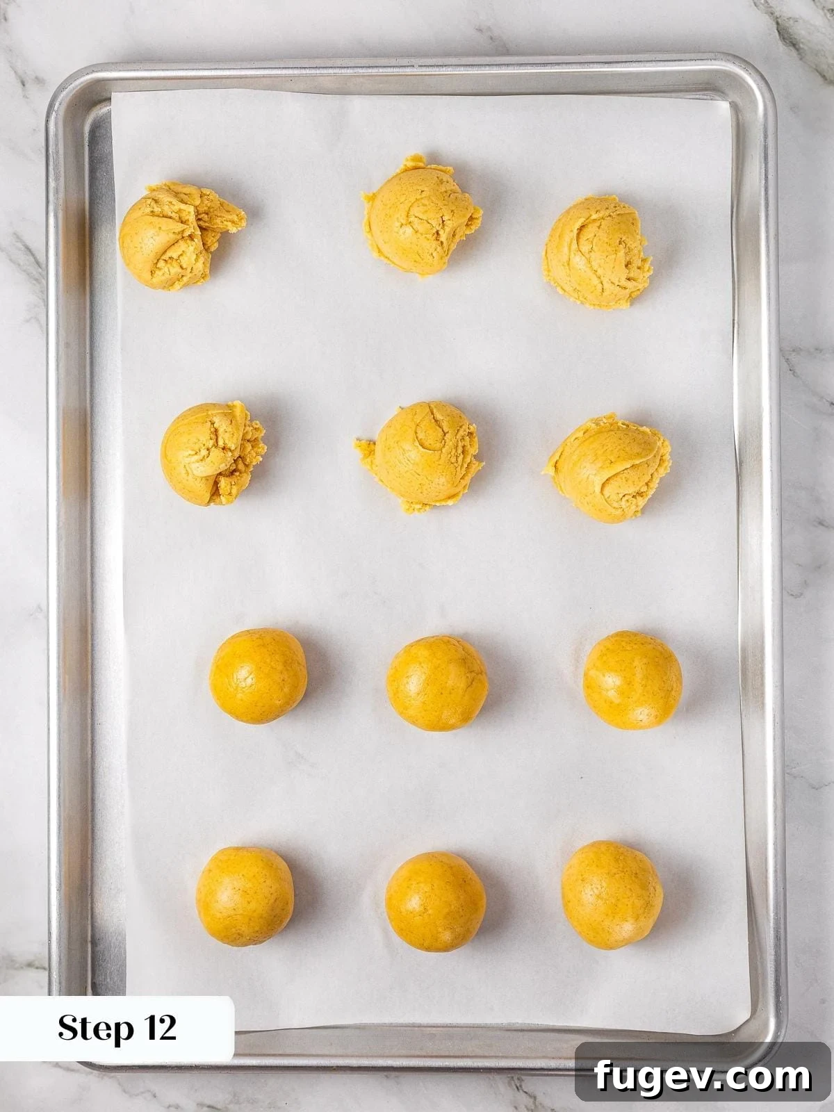 Warm Apple Spice Cookies 11 Rows of precisely scooped apple pie cookie dough balls, each with a neat, pressed indentation in the center, resting on parchment paper before being filled with apple mixture.