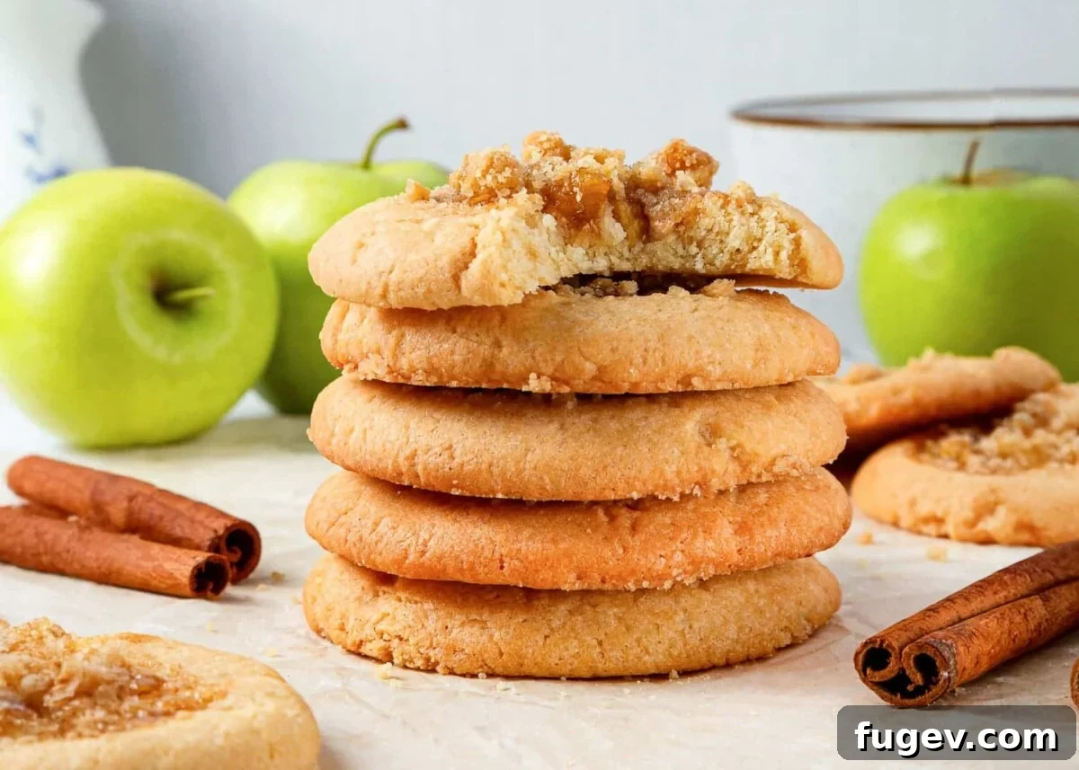 Warm Apple Spice Cookies 4 Baked apple pie cookies elegantly displayed next to fresh whole green apples and cinnamon sticks, highlighting their rustic charm and delicious, wholesome ingredients.
