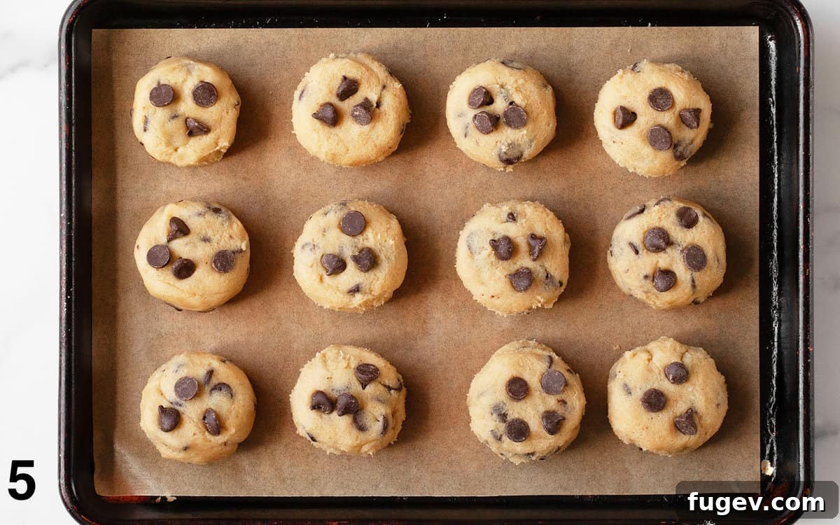Fudgy Cookie Brownies 6 Portioned and shaped chocolate chip cookie dough disks neatly arranged on a parchment paper-lined baking pan, ready for freezing.