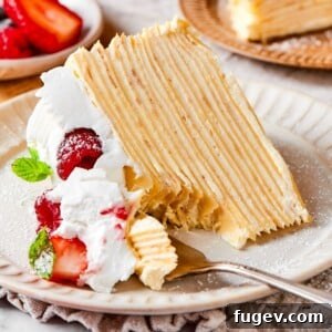 A lifted bite of crepe cake featuring soft creamy layers and a smooth vanilla texture.