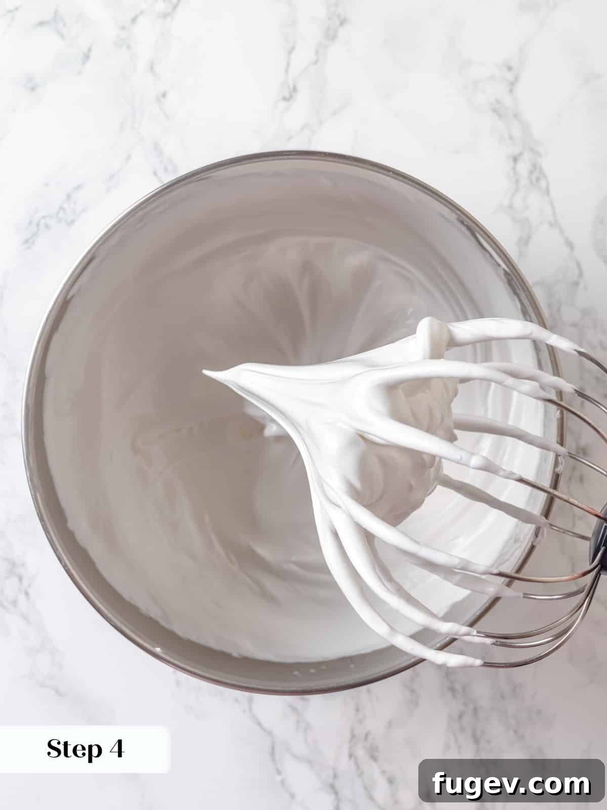 Silky Chocolate Swiss Meringue Buttercream 7 The meringue has been whipped to stiff, glossy peaks in a stand mixer, demonstrating its stable and airy consistency after cooling.