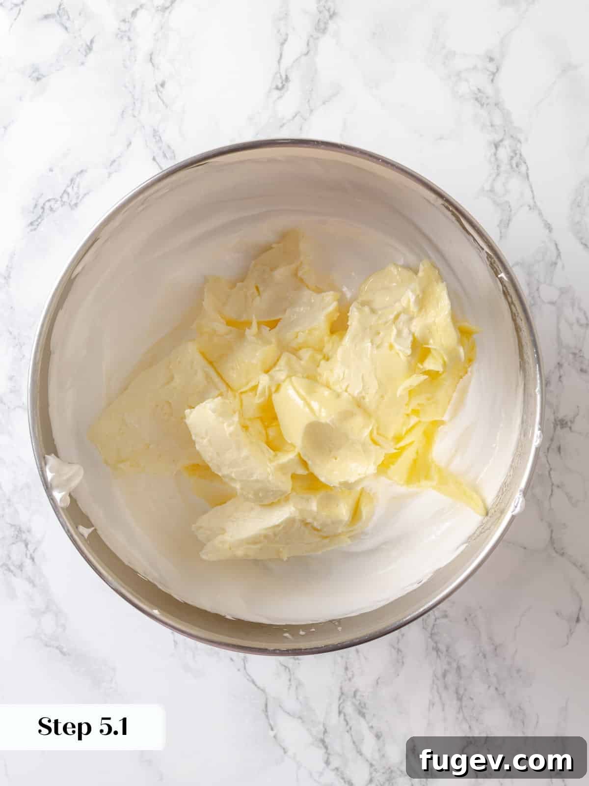 Silky Chocolate Swiss Meringue Buttercream 8 Softened butter pieces are carefully added into the cooled, whipped meringue within the stand mixer, initiating the emulsification process for the buttercream.