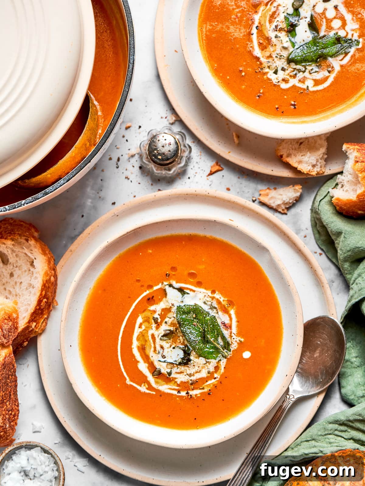 Creamy Vegan Pumpkin Harvest Soup 9 A vibrant bowl of bright orange vegan pumpkin soup, artfully topped with a swirl of rich coconut cream and a delicate drizzle of olive oil, ready to be served.