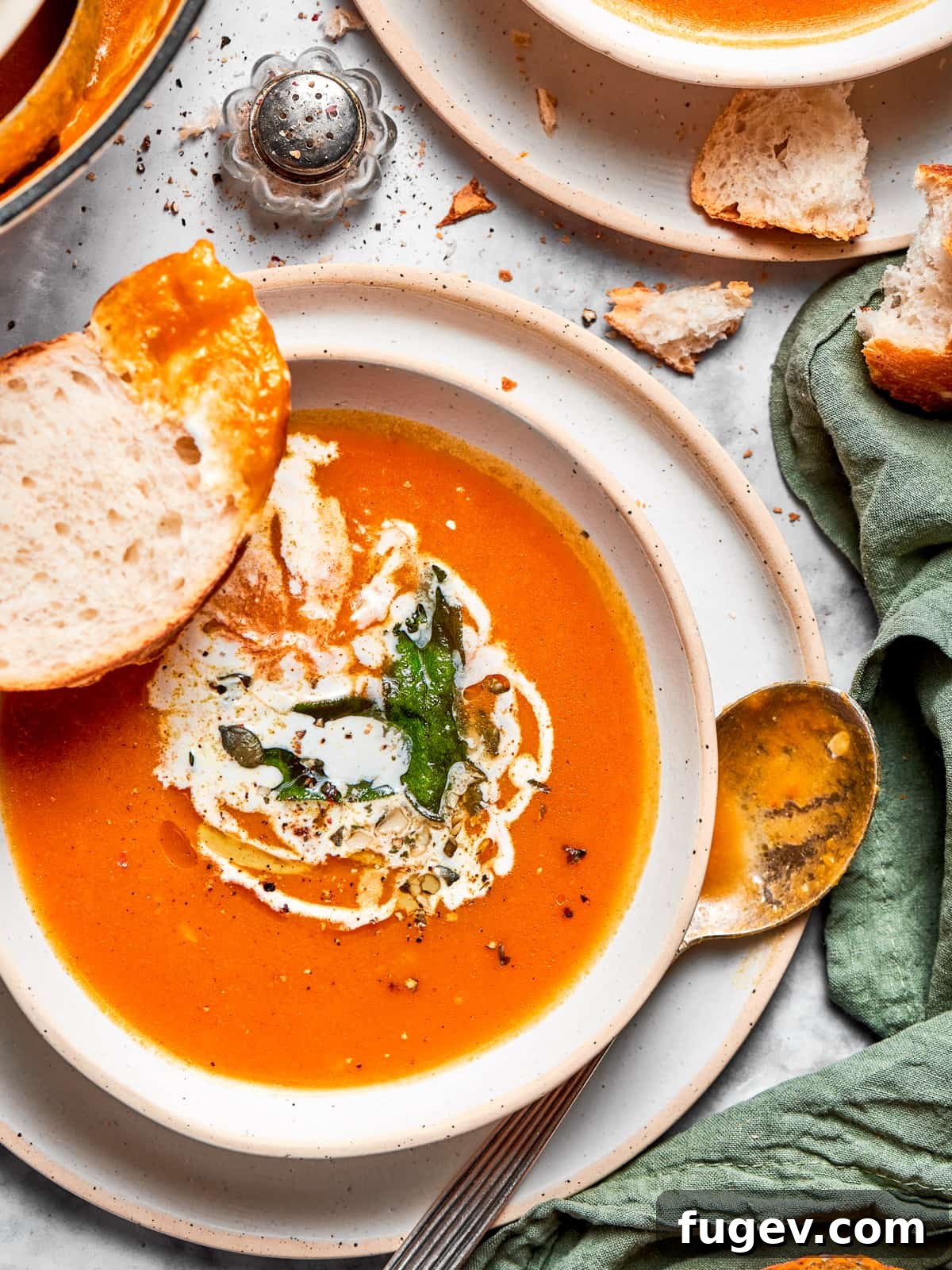 Creamy Vegan Pumpkin Harvest Soup 10 A bowl of rich vegan pumpkin soup, elegantly served with soft pieces of torn crusty bread arranged around it, inviting dipping.