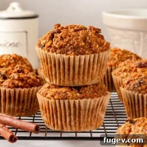 Whole grain morning glory muffins stacked together with cinnamon sticks alongside them.
