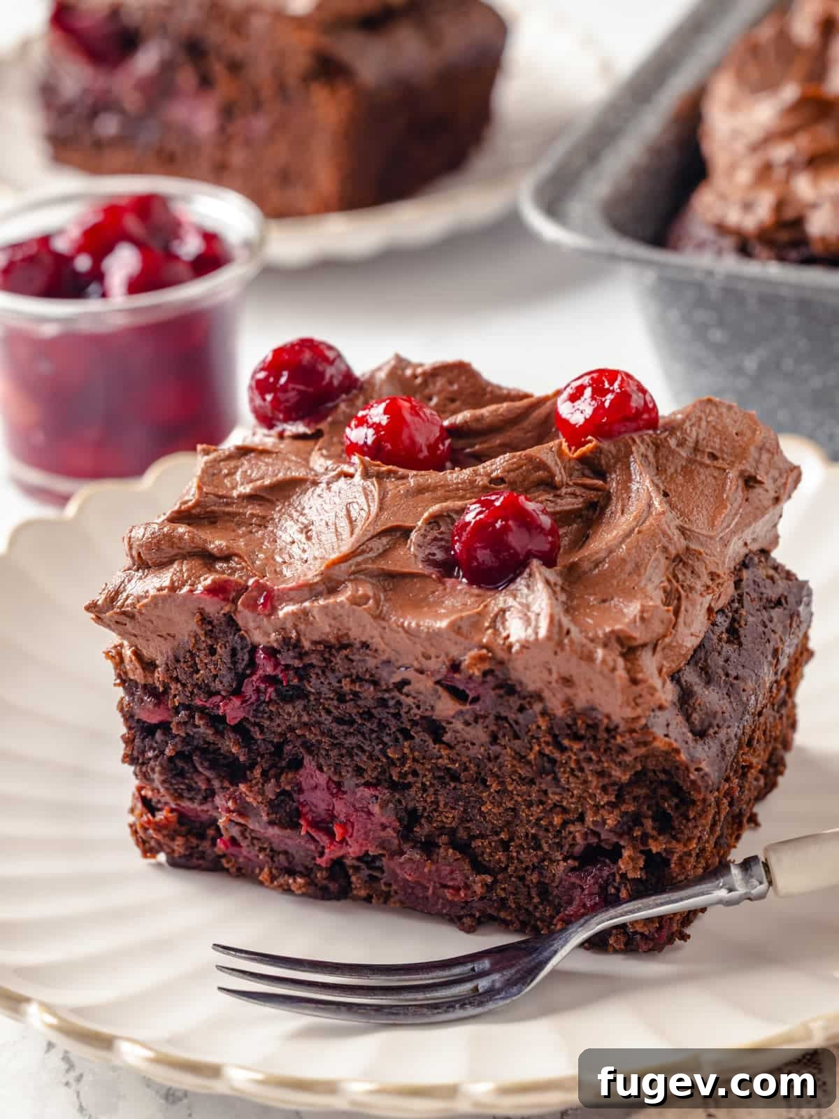 Velvet Chocolate Cherry Indulgence 2 Slice of chocolate cherry cake topped with textured frosting and fresh cherry garnish.