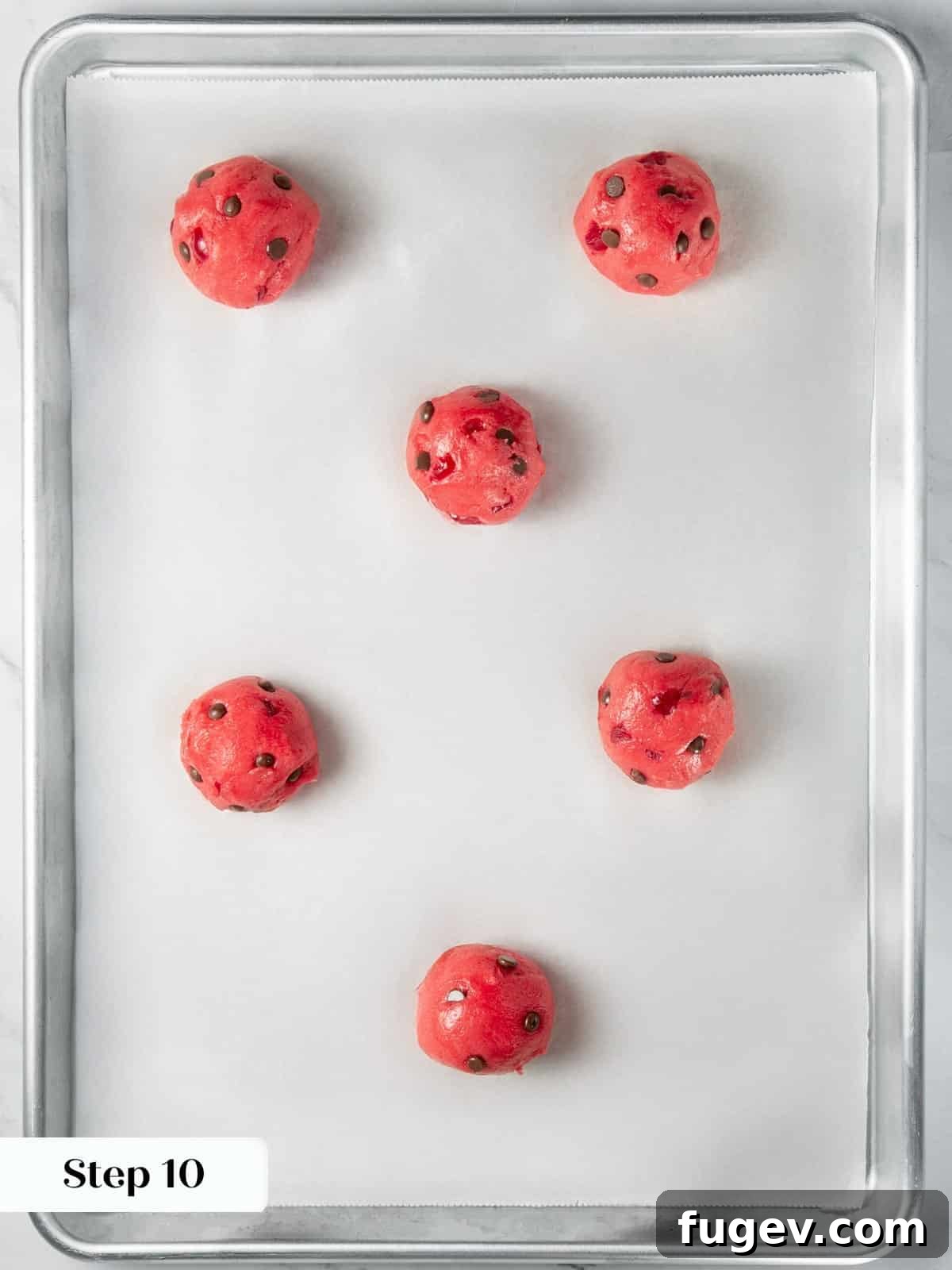 Luscious Cherry Chocolate Chip Cookies 15 Perfectly rolled cherry cookie dough balls placed on a parchment-lined baking sheet for baking.