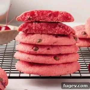 Cherry chocolate chip cookies arranged on a cooling rack, one broken open to show the inside.