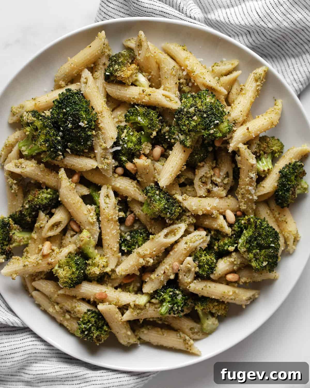 Golden Roasted Broccoli Pesto Pasta 2 A plate of roasted broccoli pesto pasta, showcasing vibrant green pesto coating penne noodles with visible pieces of roasted broccoli.