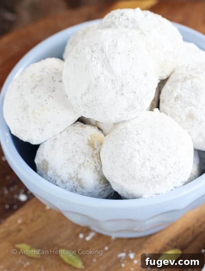 Fragrant Cardamom Walnut Snowdrifts 2 Delicious Cardamom Walnut Snowballs coated in powdered sugar, perfect for a festive holiday celebration.