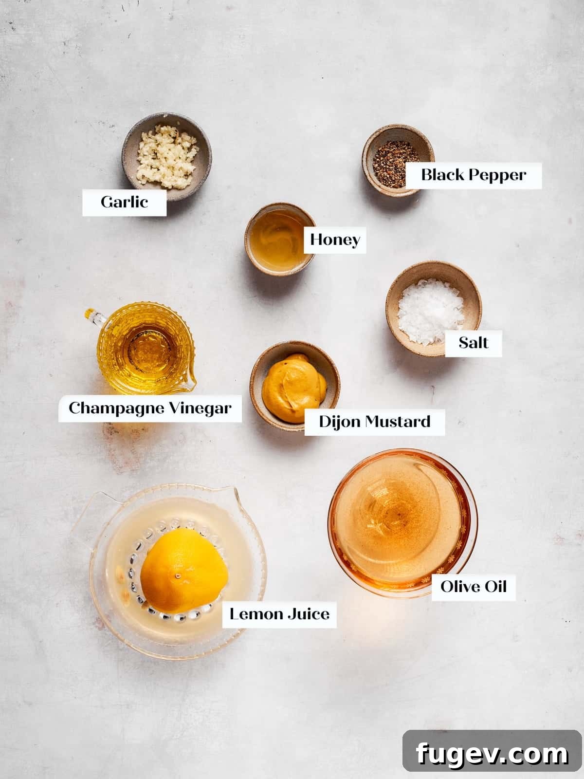 Sparkling Champagne Vinaigrette 4 Simple ingredients laid out for making champagne vinaigrette at home, including bottles of oil and vinegar, a lemon, garlic, and honey.