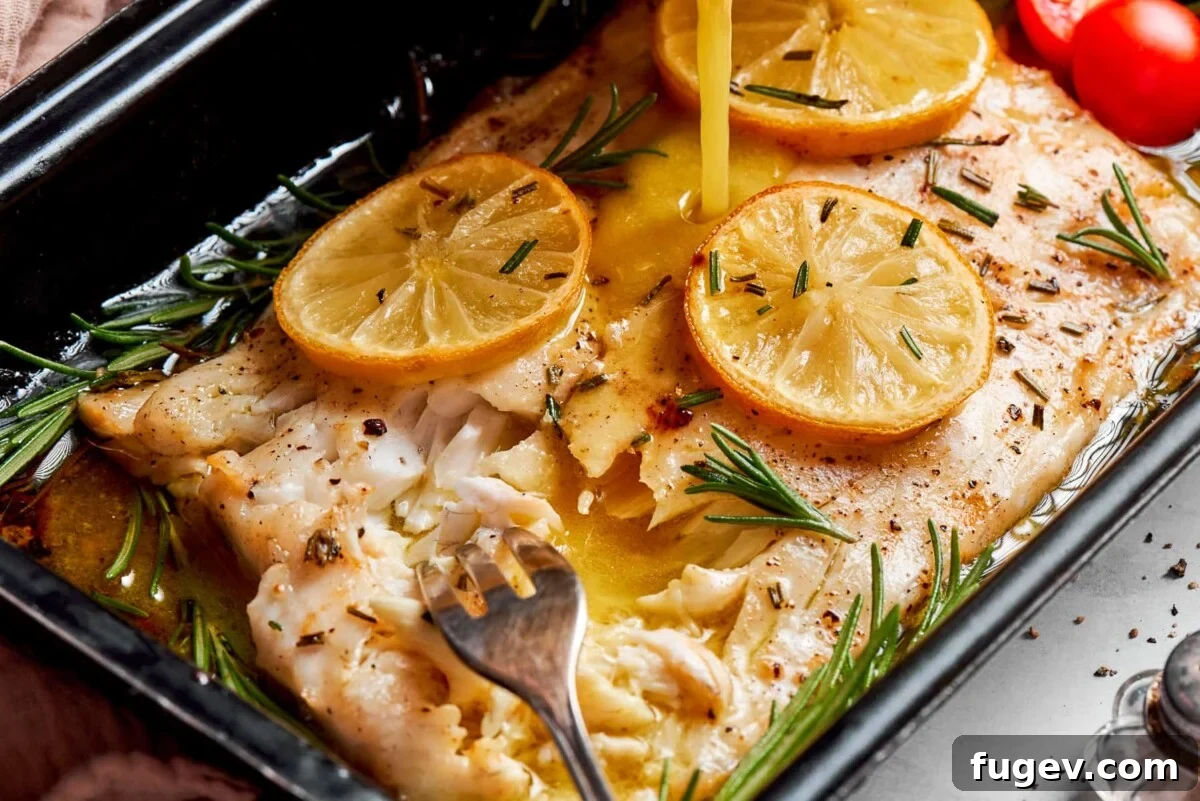 Sparkling Champagne Vinaigrette 5 Champagne vinaigrette poured over baked halibut with lemon slices on a pan, illustrating a versatile serving suggestion.
