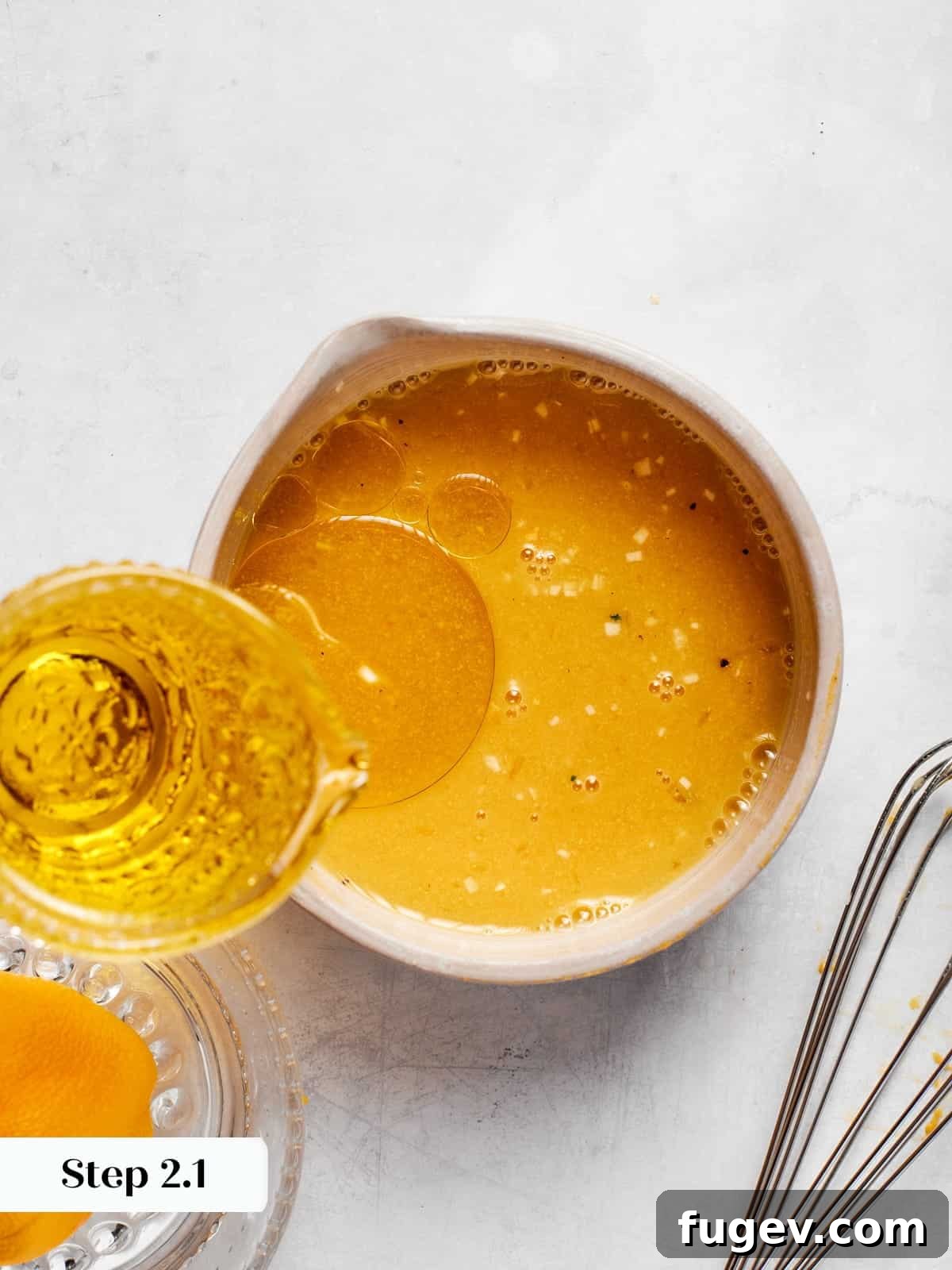 Sparkling Champagne Vinaigrette 7 Olive oil slowly poured into champagne vinaigrette while whisking to combine, showing the emulsification process.