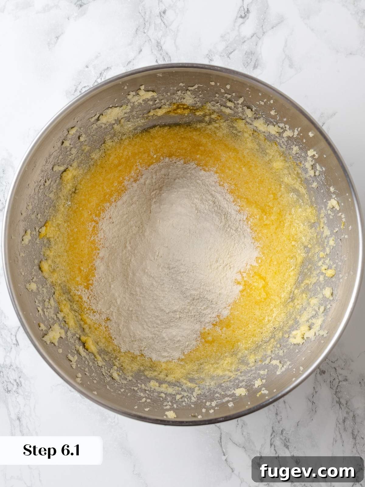 Gently folding the flour mixture into the lemon cake batter, ensuring even distribution without overworking the gluten.
