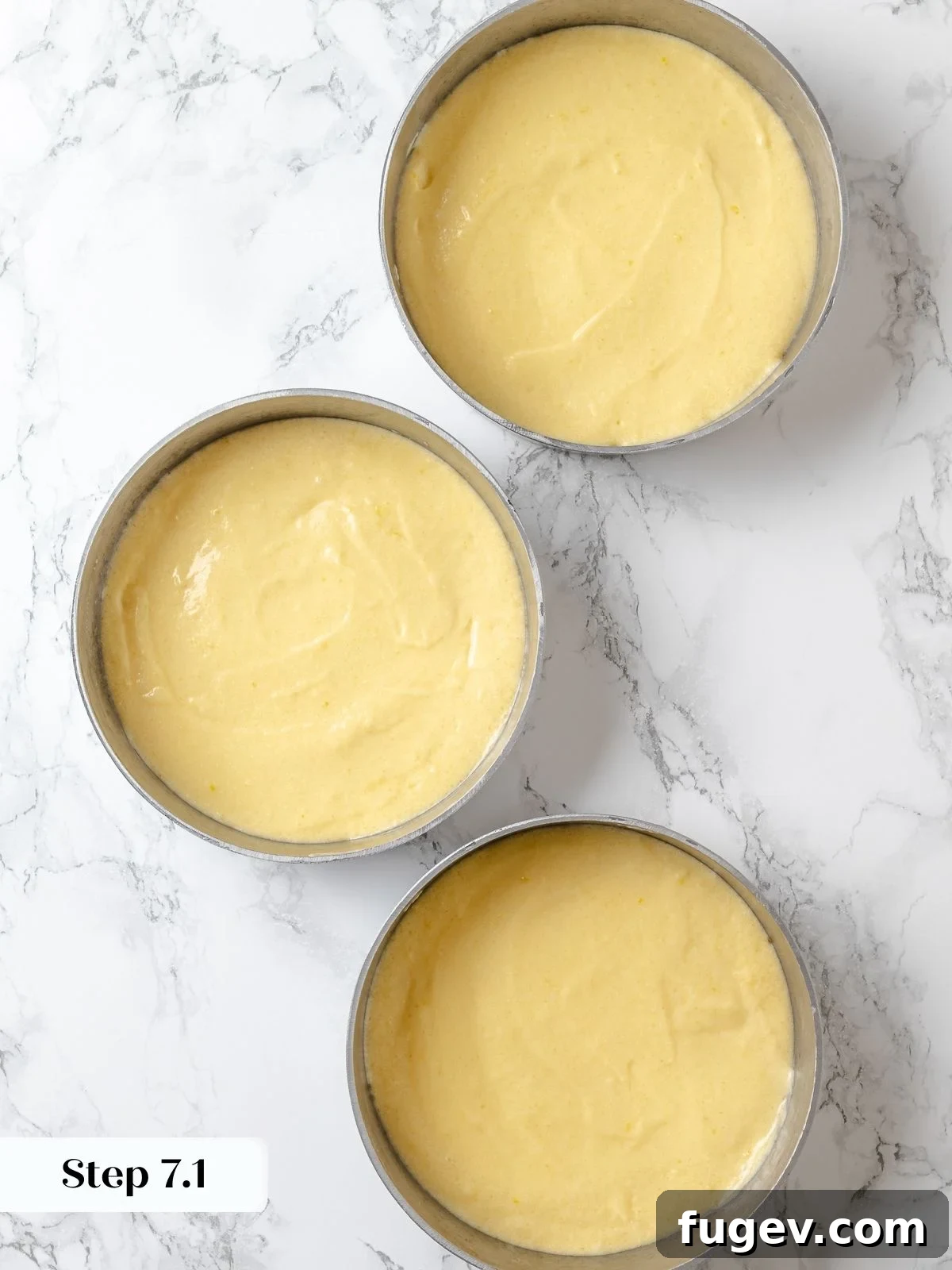 Lemon cake batter evenly divided among three meticulously prepared round cake pans, ensuring uniform layers.