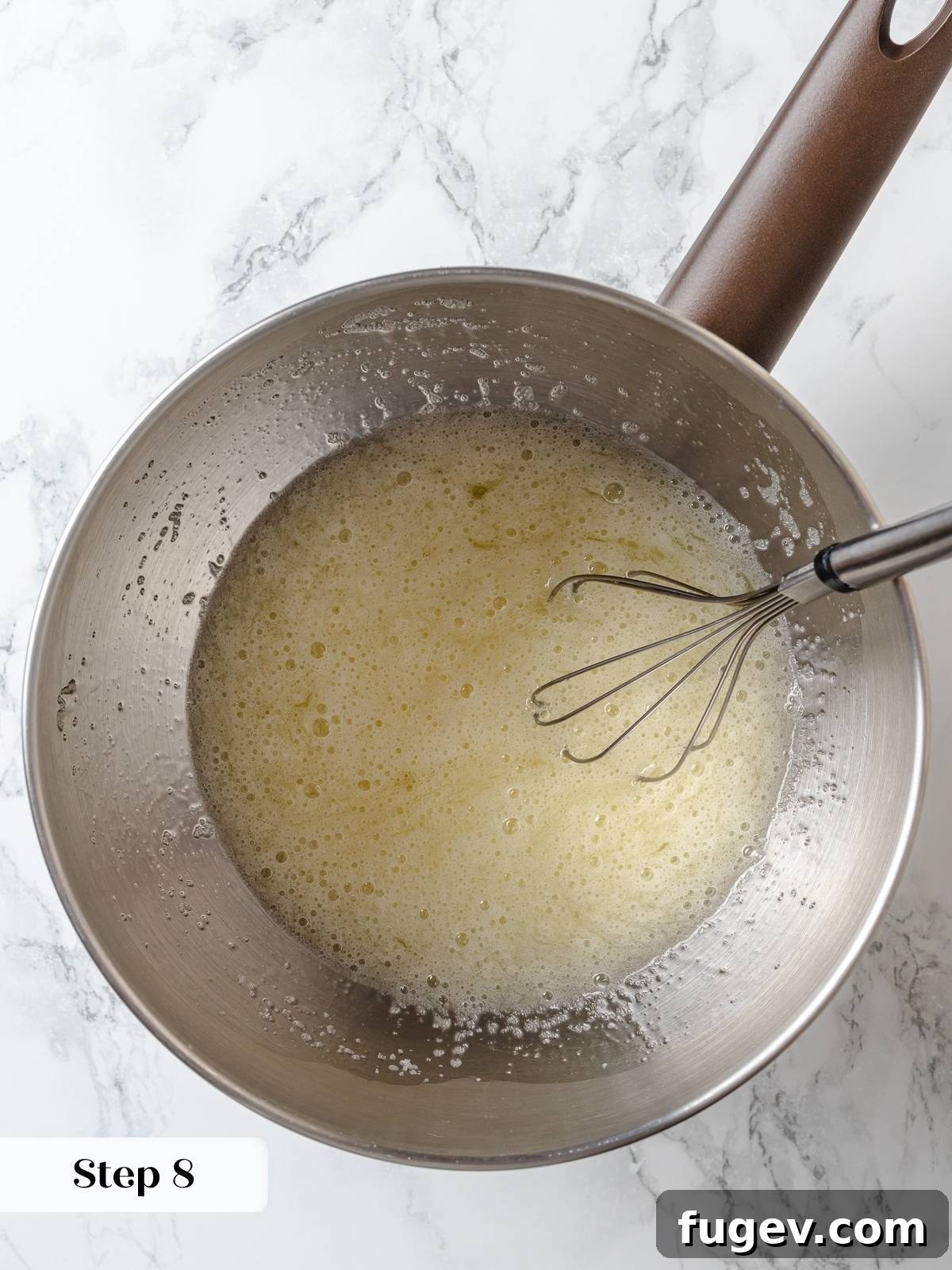 Whisking egg whites and sugar over warm water until smooth, foamy, and the sugar fully dissolves, preparing a stable Swiss meringue base.