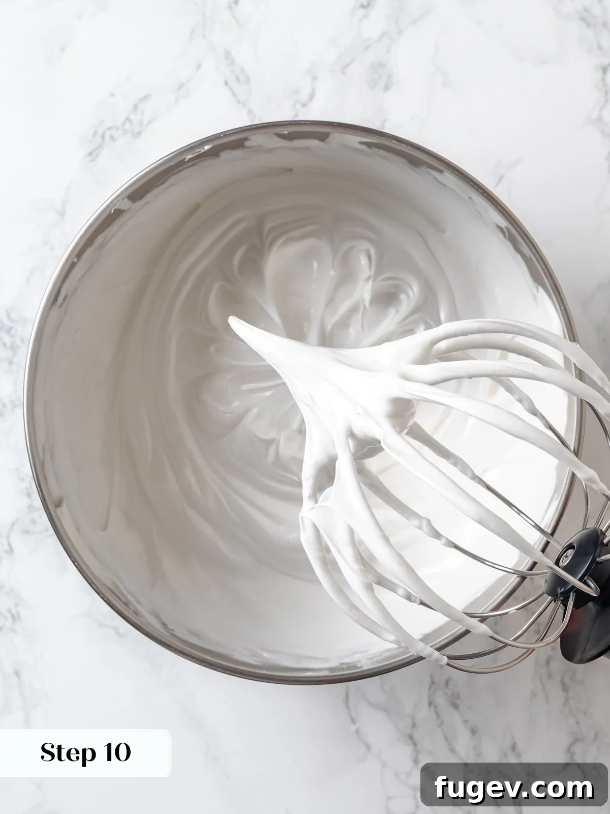 Swiss meringue actively whipping to stiff, glossy peaks, forming the airy and stable base for the lemon buttercream frosting.