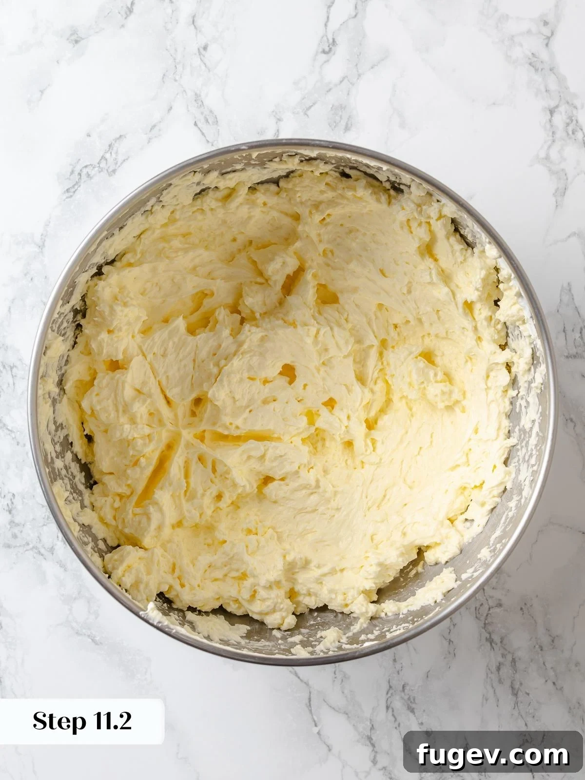 Softened butter is fully incorporated into the meringue, transforming it into a luxurious, silky buttercream frosting.