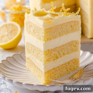 A single slice of lemon cake presented on a delicate scalloped plate, featuring smooth buttercream and a soft, airy crumb.