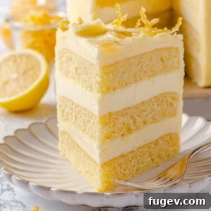 A beautifully presented slice of lemon cake on a scalloped plate, showcasing its smooth buttercream and soft, moist crumb.