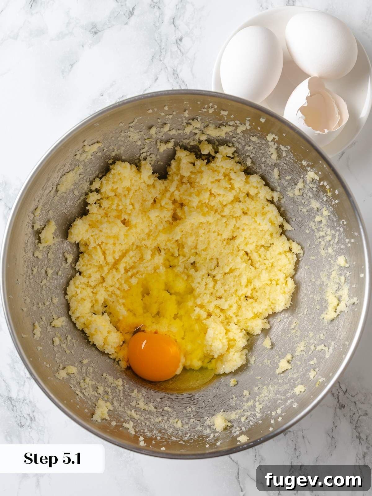 Eggs are added one at a time to the lemon cake batter, carefully incorporated to achieve perfect emulsification and texture.