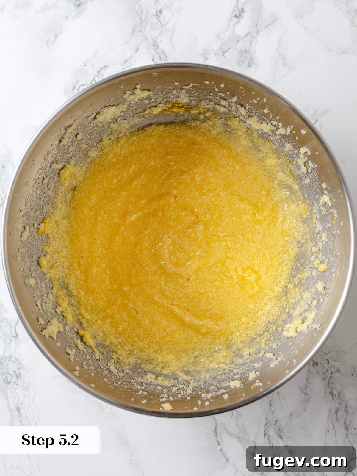 More eggs being incorporated into the creamed butter and sugar mixture, building a rich and well-emulsified lemon cake batter.