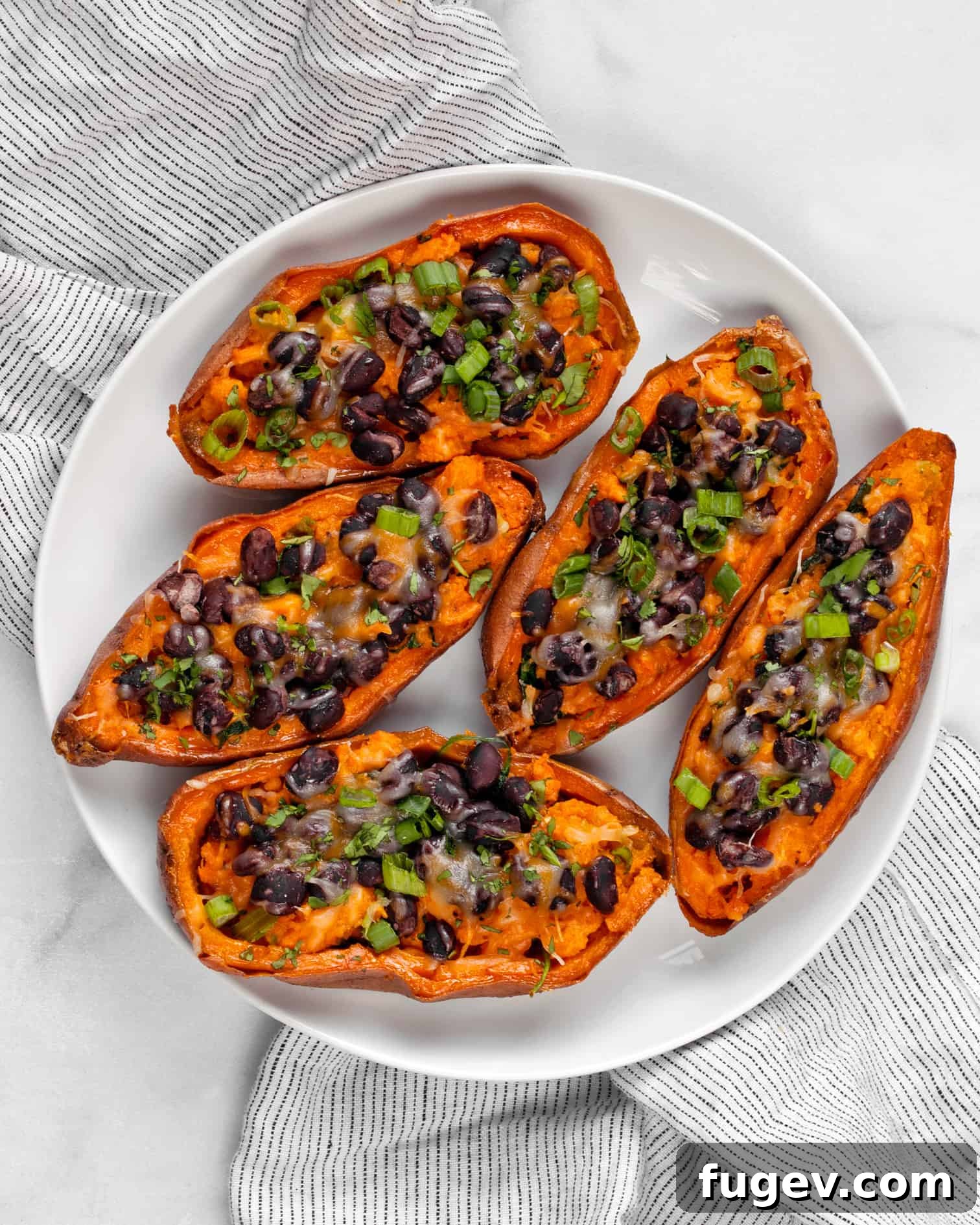 Sweet Potato Boats 3 Two halves of sweet potato skins on a white plate, showcasing the vibrant filling