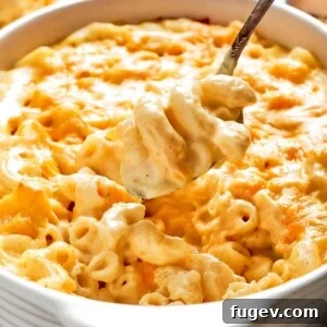 A large spoon lifting a creamy, cheesy scoop of baked mac and cheese, showcasing its rich texture and melty goodness.