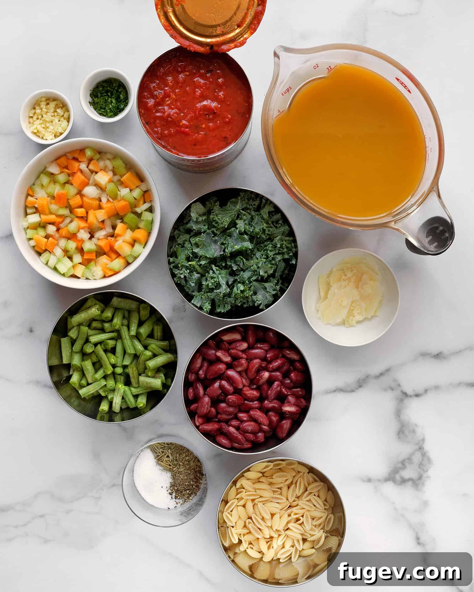 Wholesome Garden Minestrone 3 Assortment of fresh and canned ingredients including kidney beans, crushed tomatoes, olive oil, carrots, celery, onion, garlic, and fresh kale, ready for making soup.