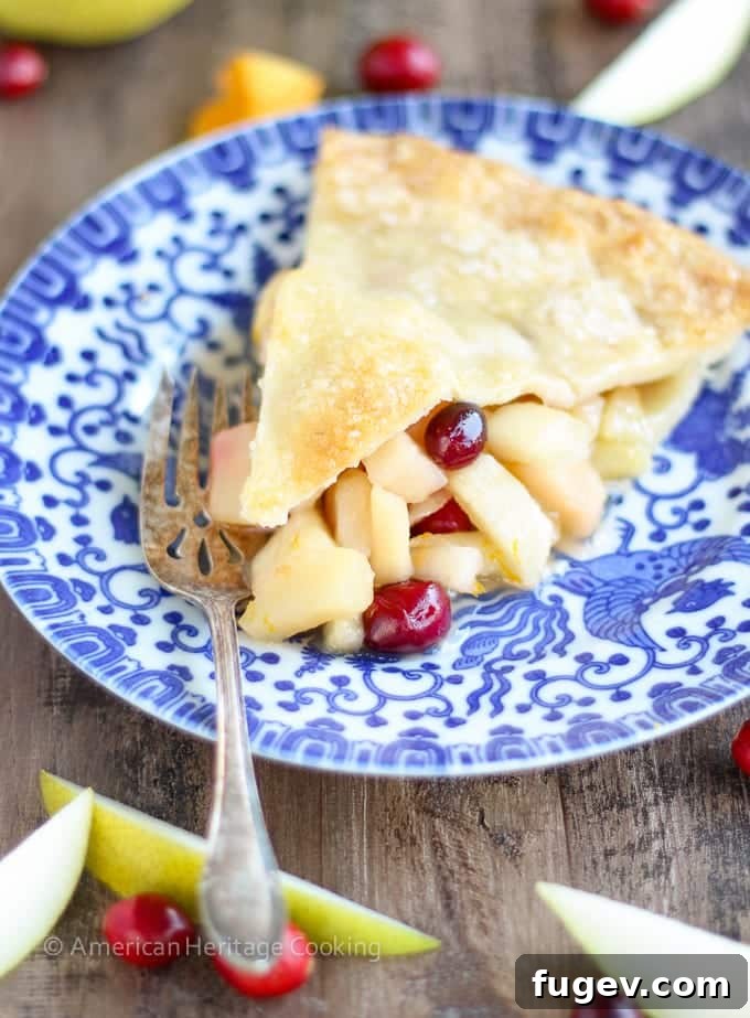 Vibrant Cranberry Orange Pear Pie 2 A beautiful slice of Cranberry Orange Pear Pie on a plate, showcasing the vibrant cranberry and pear filling and the golden, flaky crust.