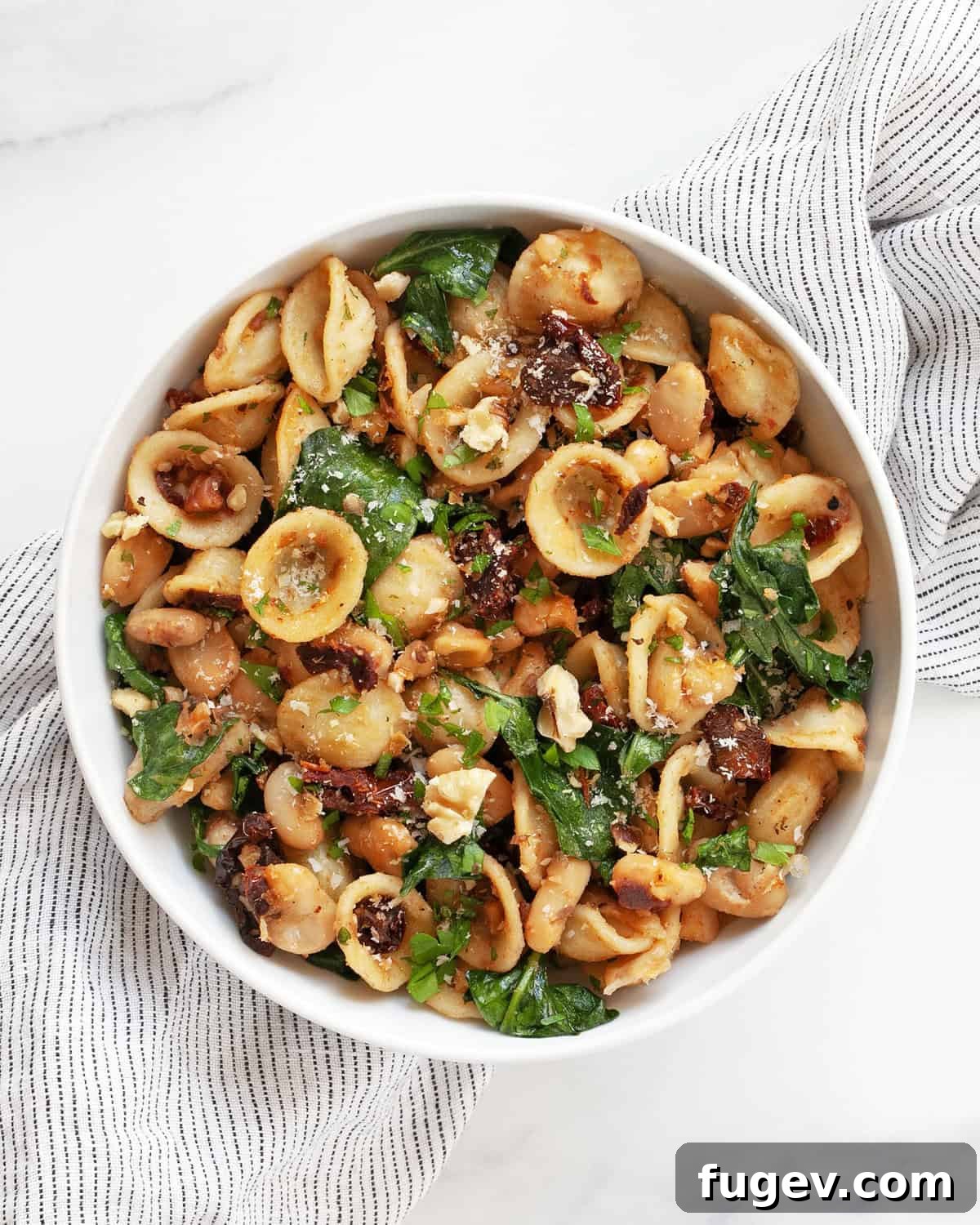 Zesty Lemon White Bean Pasta with Sun-Dried Tomatoes and Fresh Greens 5 A small, inviting bowl filled with Lemony White Bean Pasta with Sun-Dried Tomatoes, garnished with fresh herbs and cheese.