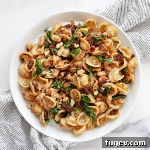 Lemony White Bean Pasta with Sun-Dried Tomatoes and Baby Greens on a plate.