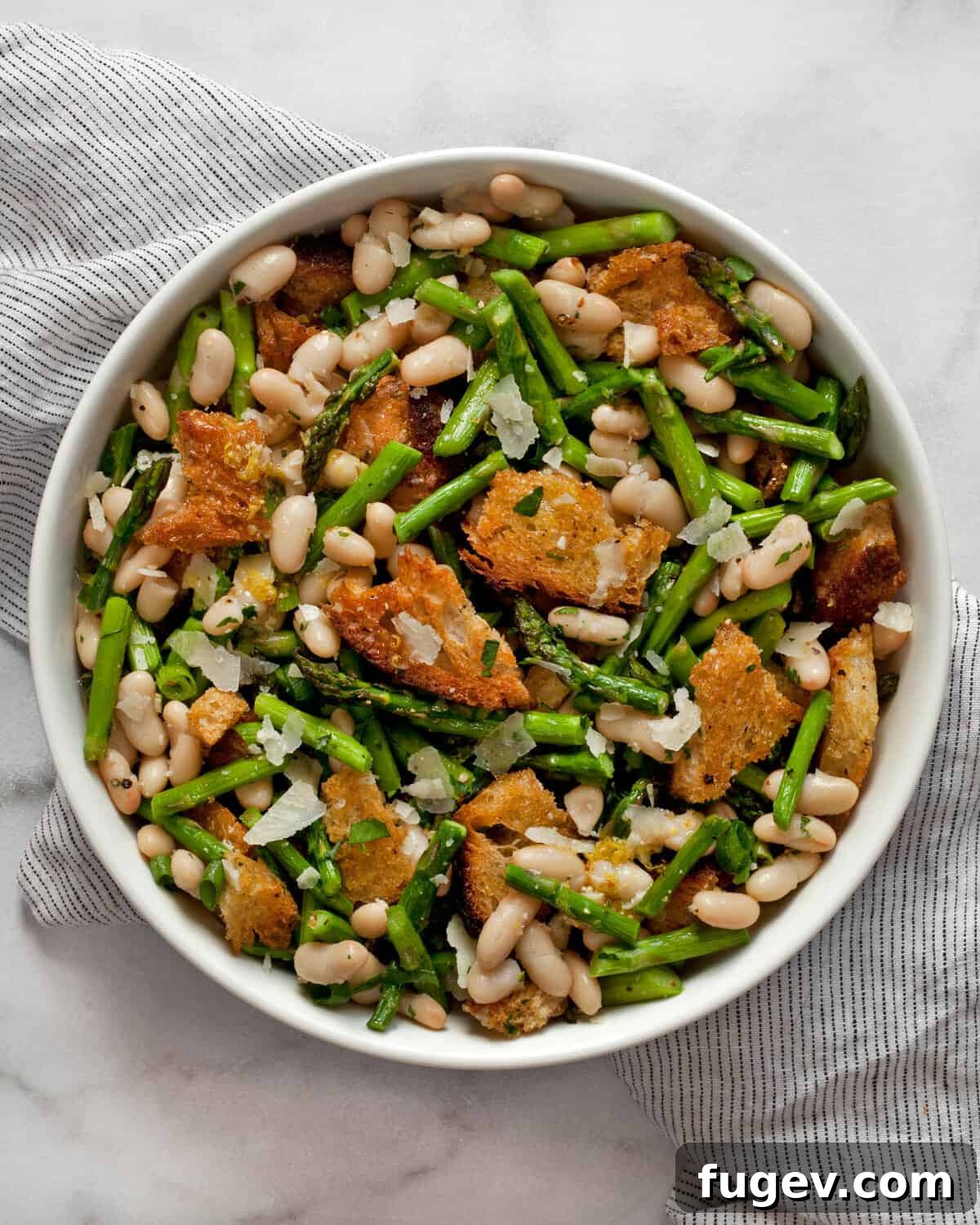 Spring Asparagus and Cannellini Bean Salad 2 A vibrant asparagus salad in a bowl, featuring roasted asparagus, cannellini beans, and golden croutons, dressed with vinaigrette.