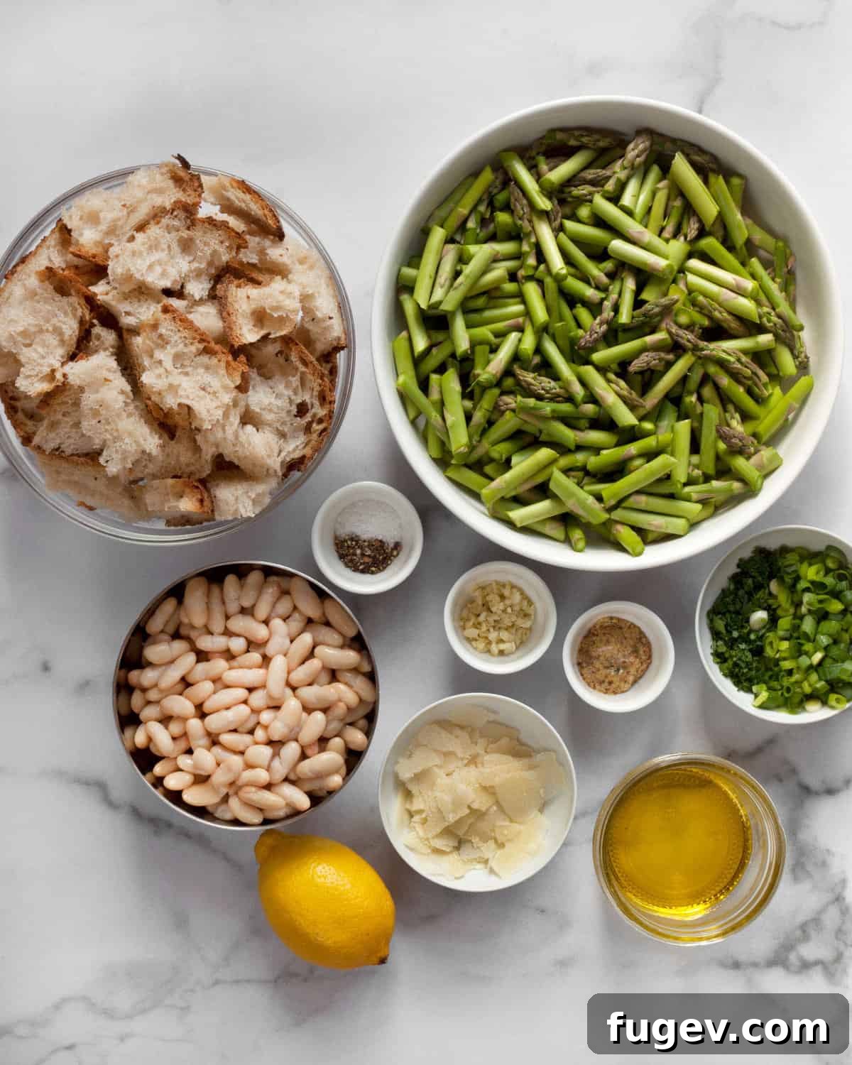 Spring Asparagus and Cannellini Bean Salad 3 Fresh ingredients laid out for asparagus salad including asparagus, sourdough bread, white beans, lemon, Parmesan, garlic, herbs, salt, pepper, and olive oil.