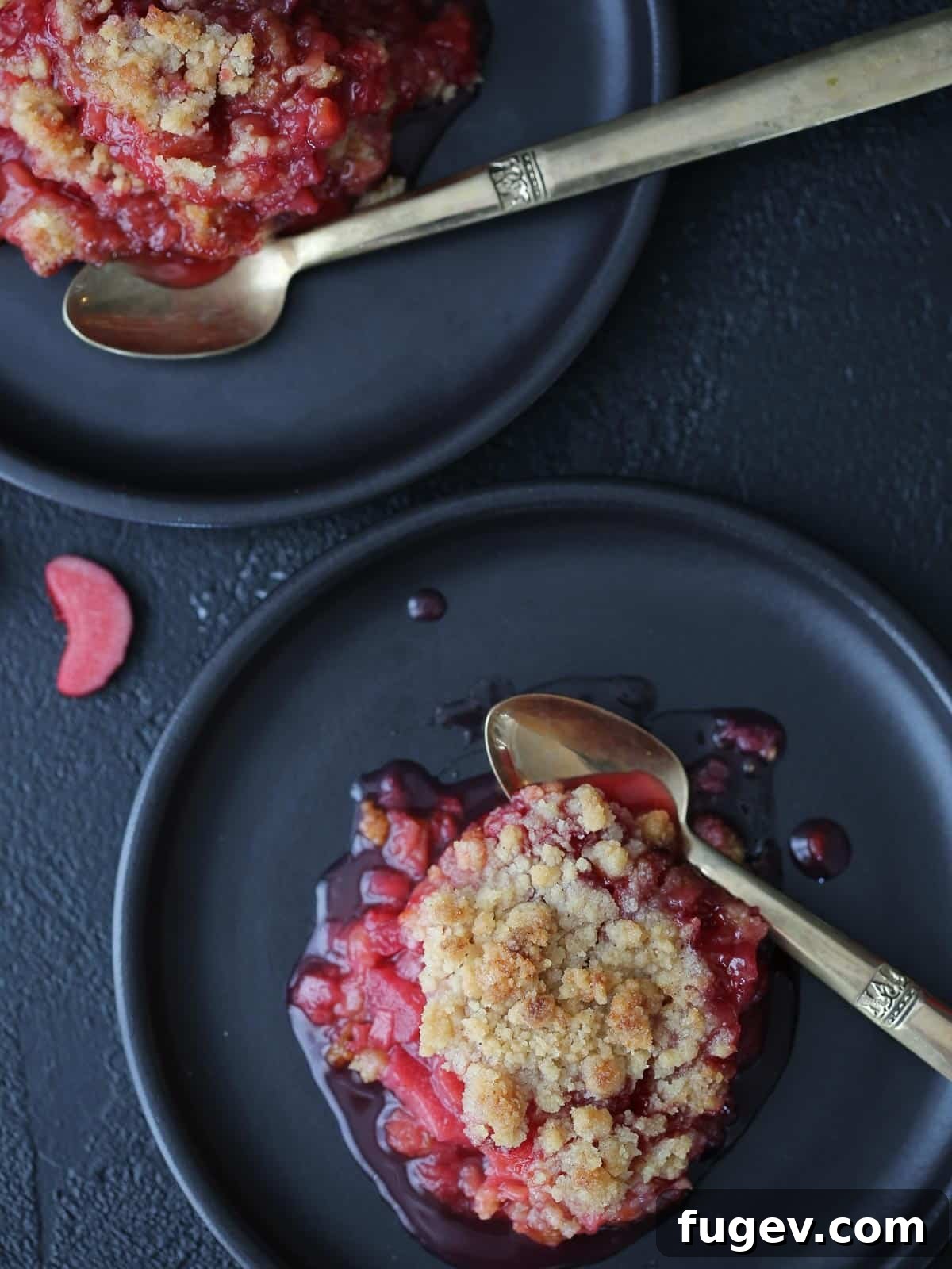 Homestyle Raspberry Rhubarb Crumble 4 A silver spoon next to raspberry rhubarb crisp with thick fruit filling.
