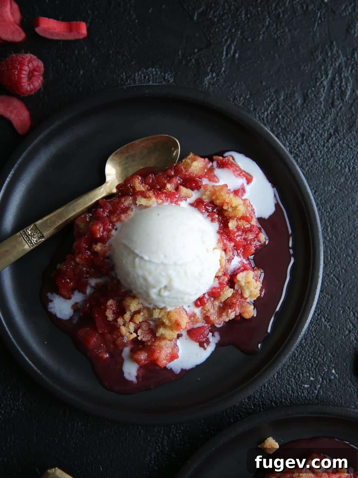 Homestyle Raspberry Rhubarb Crumble 5 Raspberry rhubarb crisp served on a black plate with a scoop of vanilla ice cream.