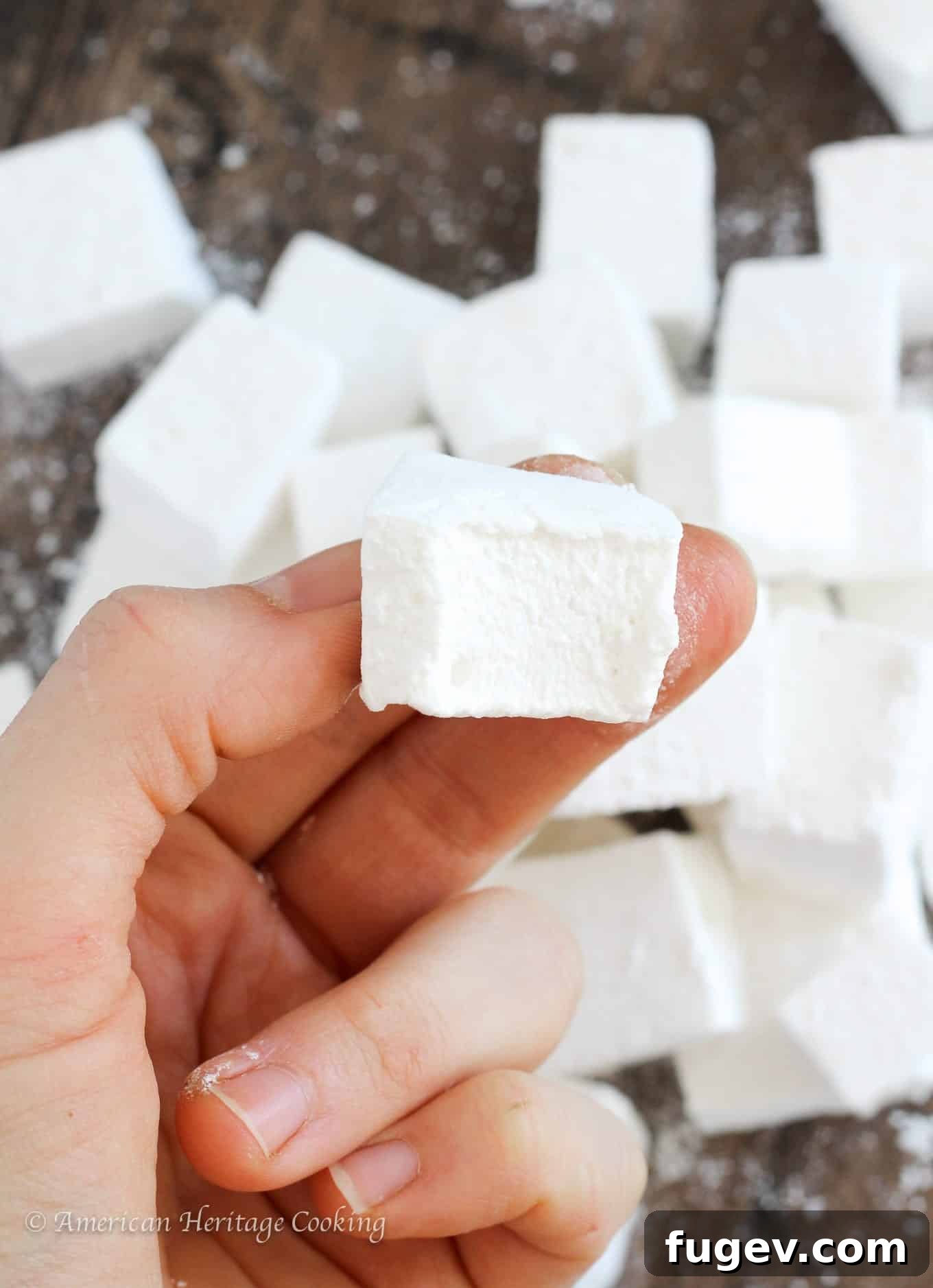 Fluffy Homemade Marshmallows 4 Hand reaching for a homemade marshmallow, showcasing its appealing softness and inviting texture.