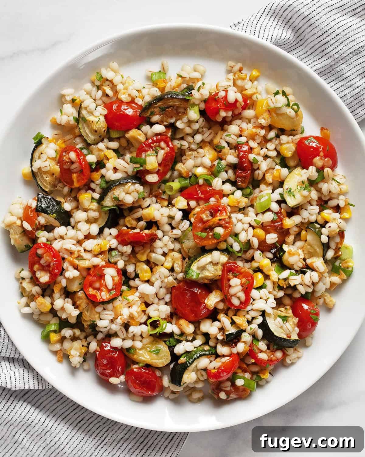 Golden Roasted Vegetable Barley Salad 2 Tomato, corn & zucchini barley salad in a rustic ceramic bowl, garnished with fresh herbs.