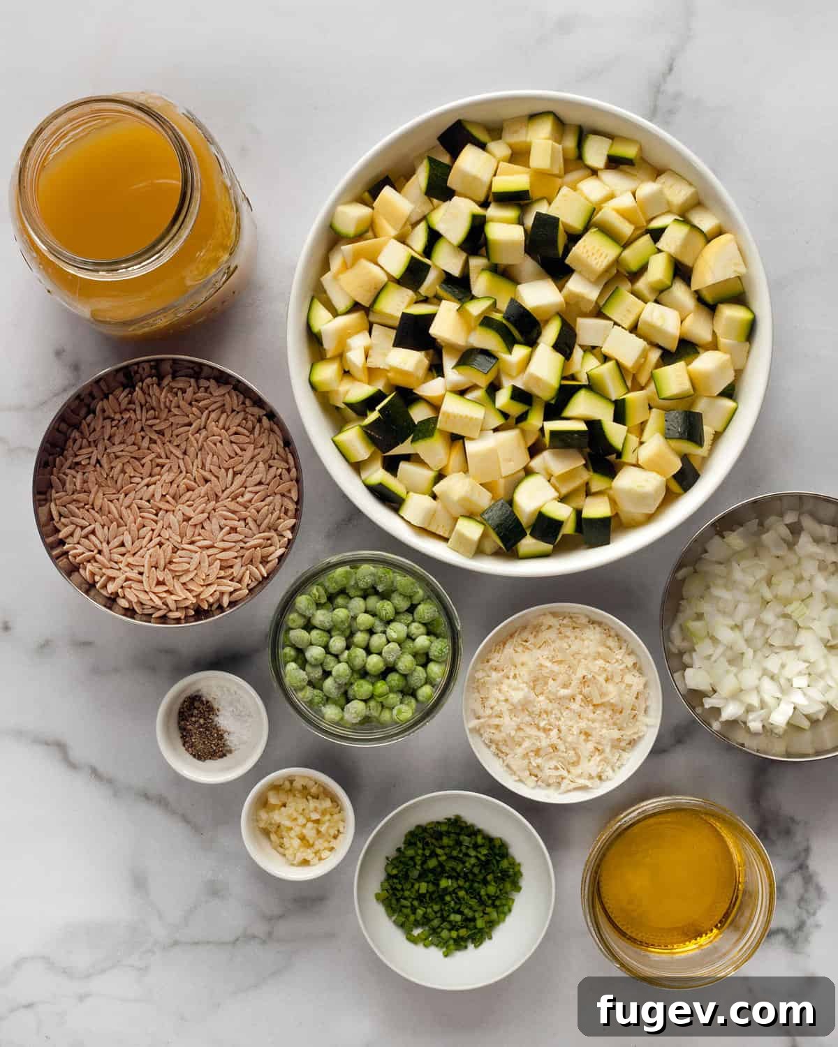 Parmesan Summer Squash Orzo 2 A flat lay of all the fresh ingredients needed for the recipe including orzo, yellow squash, zucchini, peas, Parmesan cheese, onions, garlic, vegetable broth, and chives.